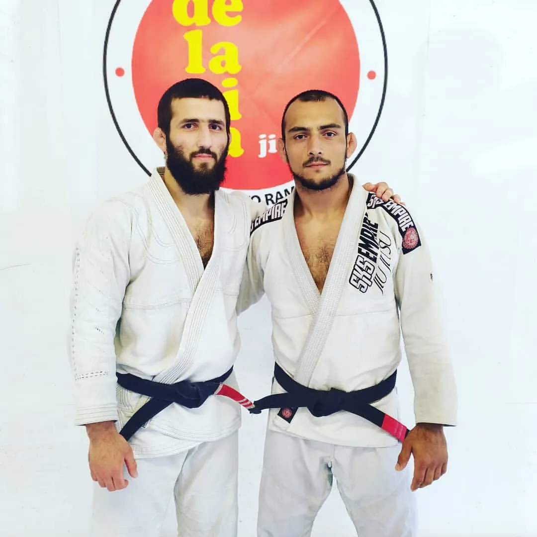Deux ceintures noires en kimono devant le logo du club