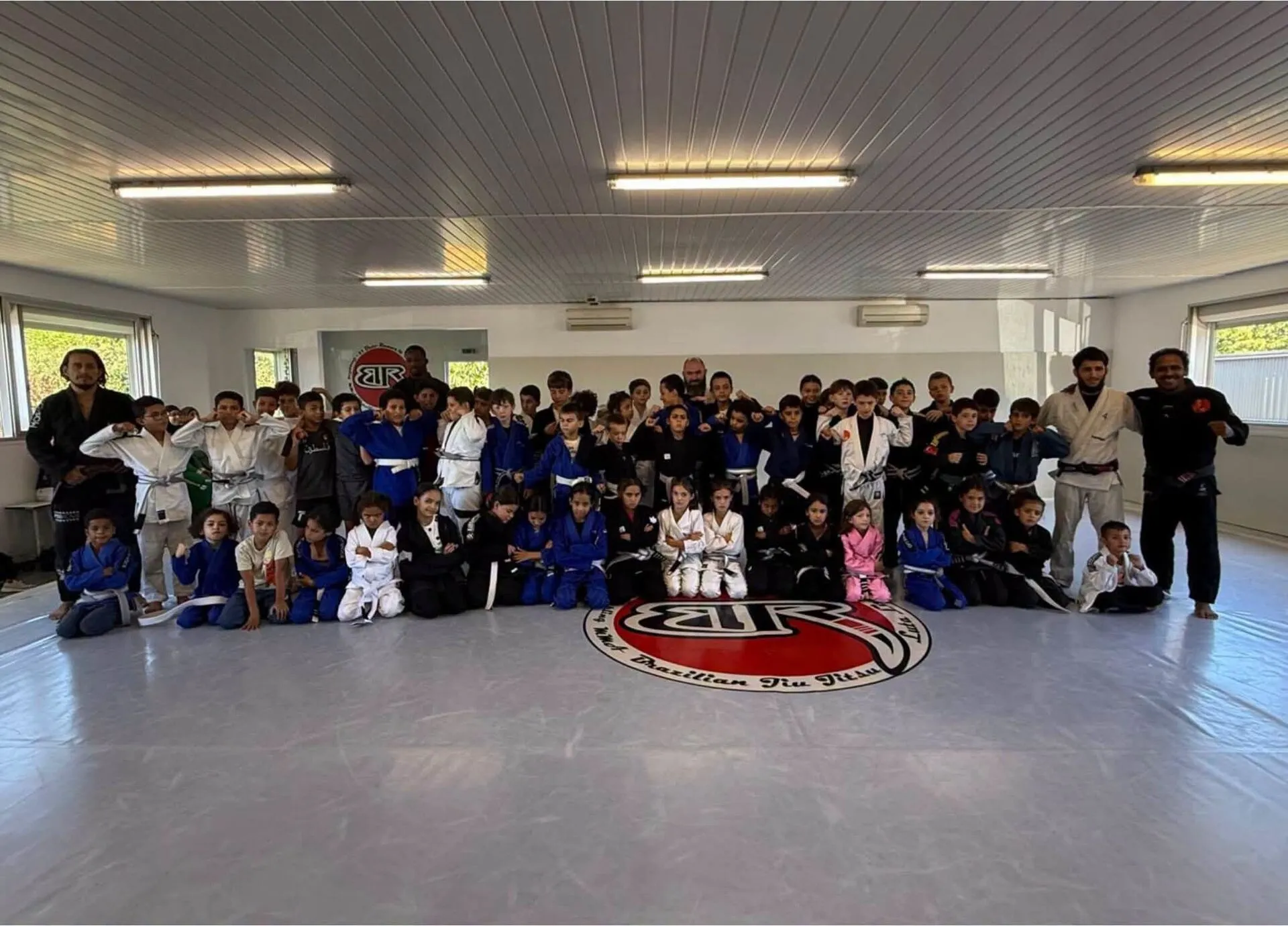 Les enfants et ados du club en kimono, réunis sur le tapis avec leurs professeurs
