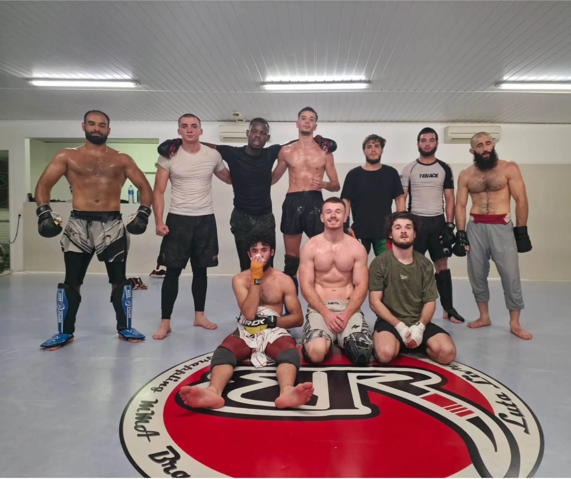 Les combattants de MMA du club réunis autour de l’emblème peint sur le tapis